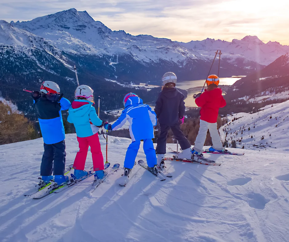 Jeunes sur des skis en haut d'une montagne enneigée regardant l'horizon